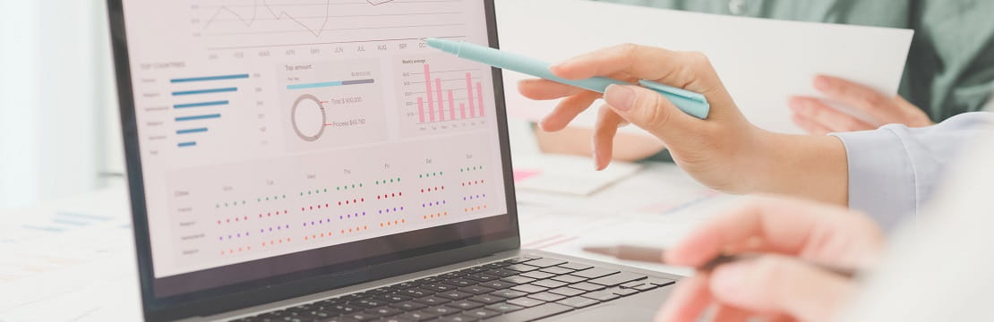 Laptop with a chart displayed on the screen is being pointed to by a person holding a pen
